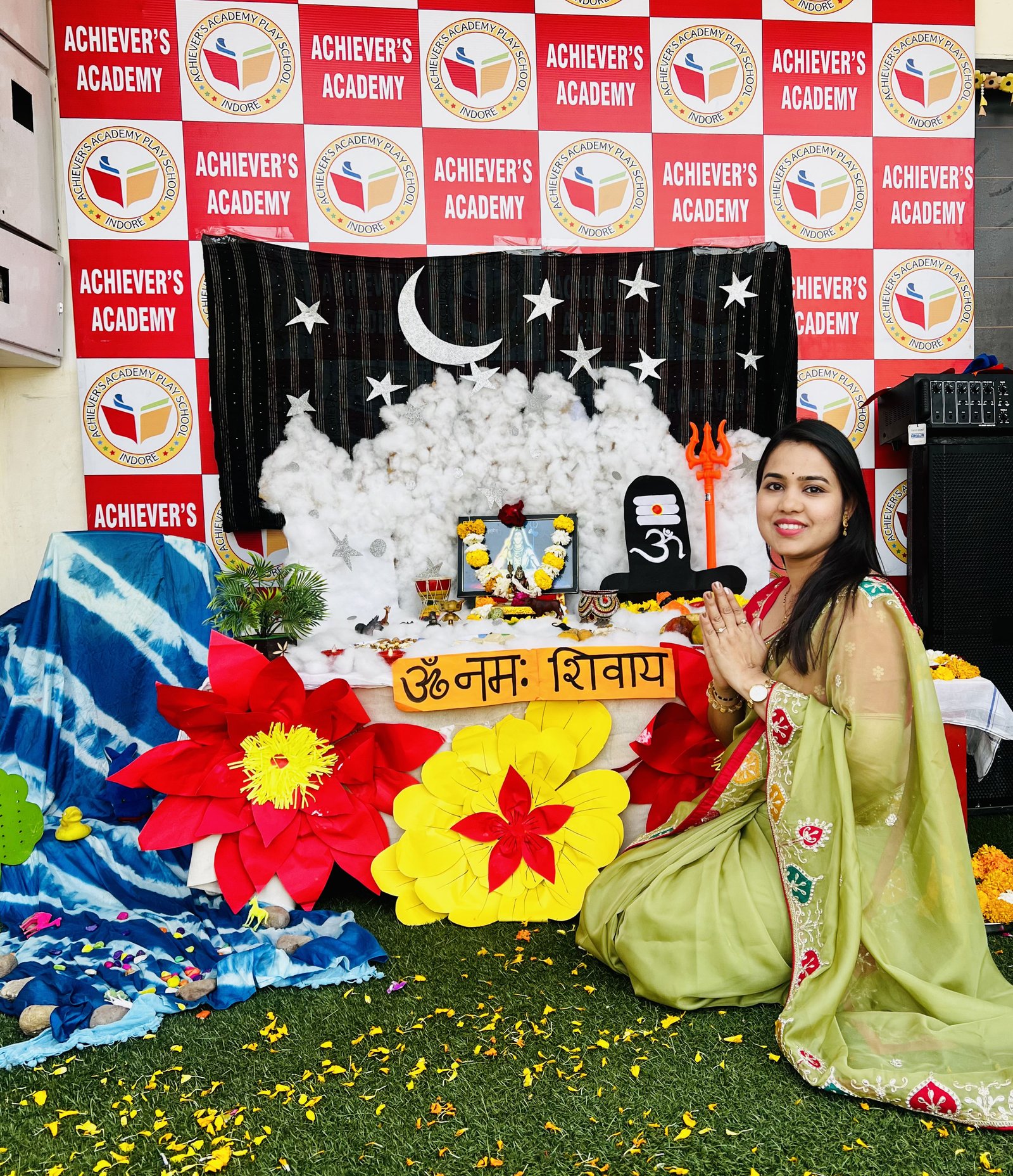 Maha Shivratri Puja - Teacher sitting in prayer pose in front of decorative Shivratri shrine
