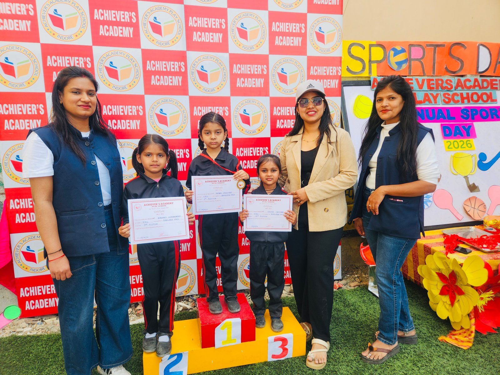 Annual Sports Day Prizes - Students holding certificates on podium with teachers