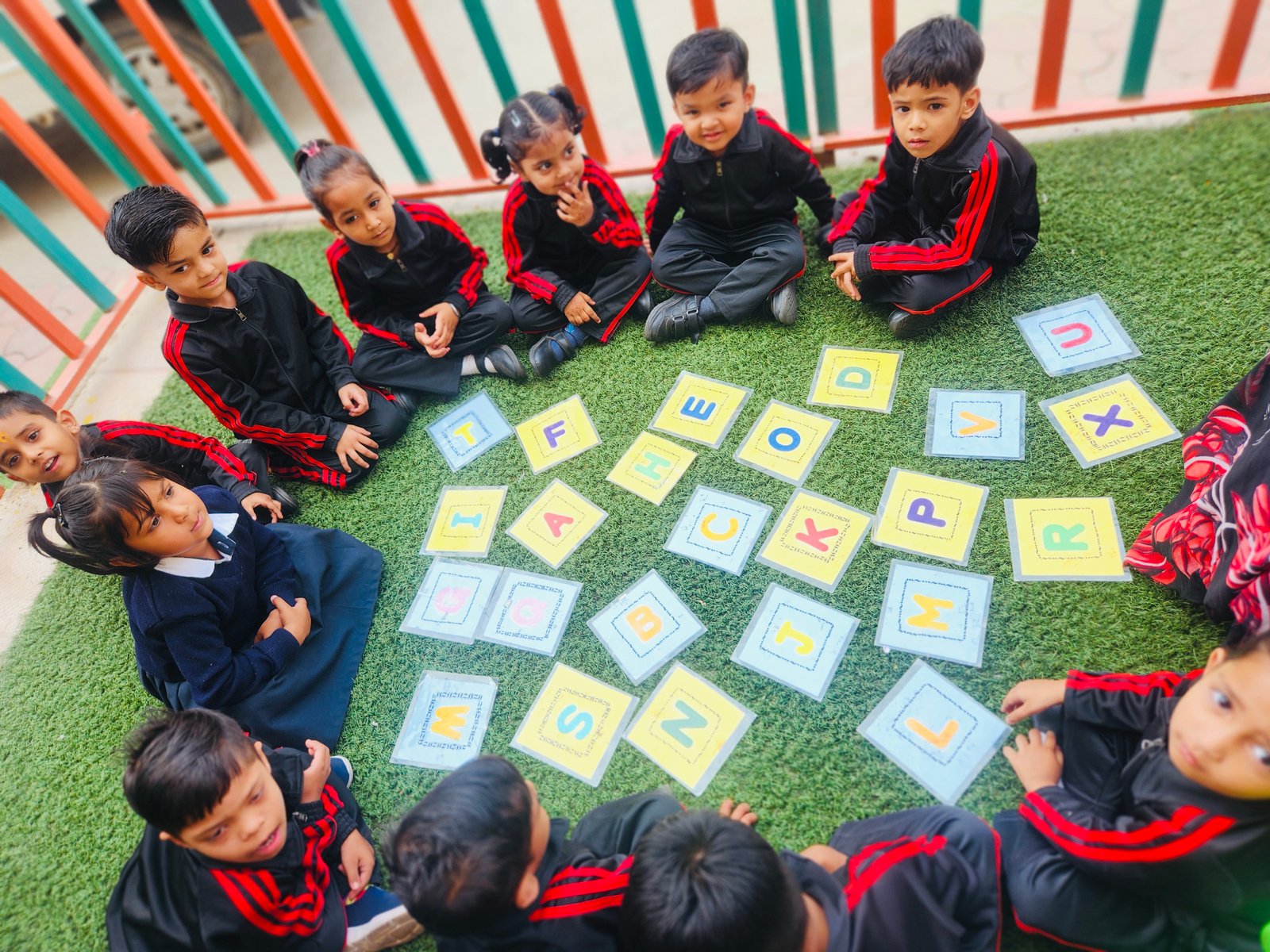 Circle Time Alphabet Activity - Children sitting in a circle on artificial grass learning alphabets